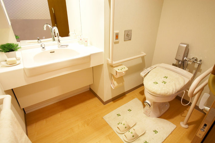 洗面台の蛇口は自動給水。トイレは介助バー、コールボタンがあり、車いすでも十分な広さがあります。